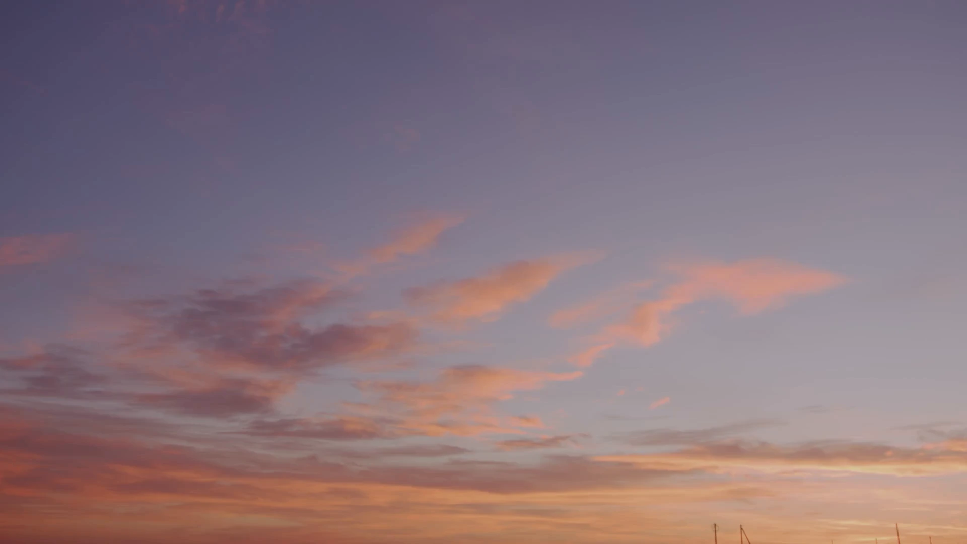 Soft pink and orange clouds across an open violet evening sky.
